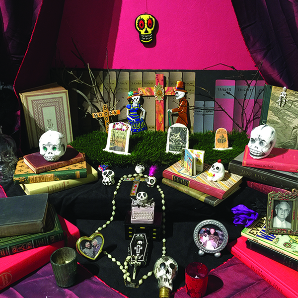 Dia de los Muertos altar with skulls, photos and books.